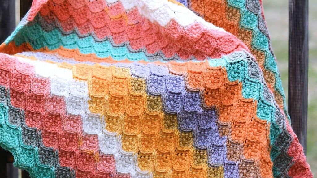 A dragon scale crochet baby blanket, in various colors.
