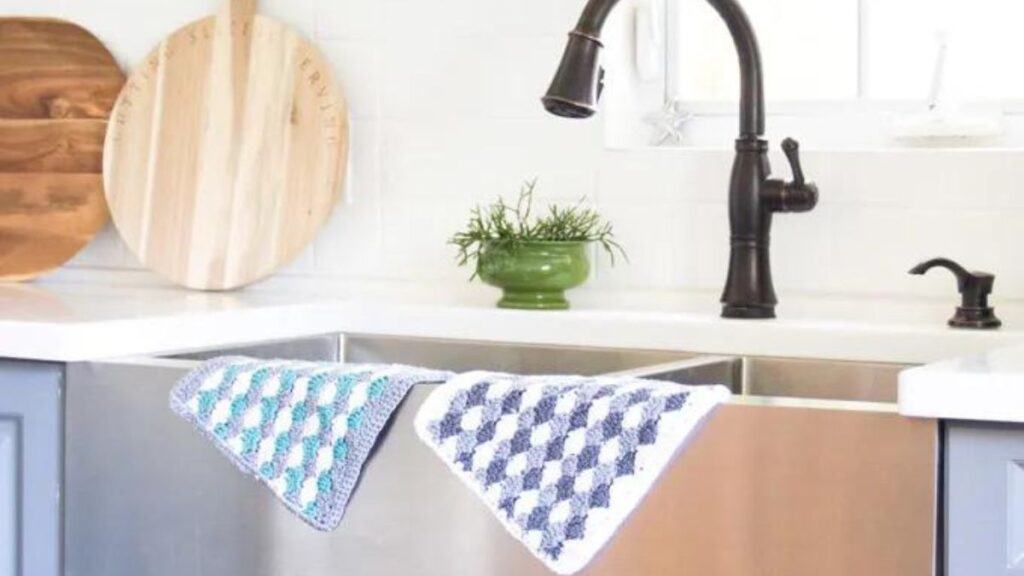 Two seashell dish cloths draped over a sink.