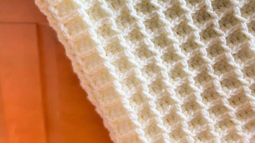  A cream colored waffle stitch crochet blanket.