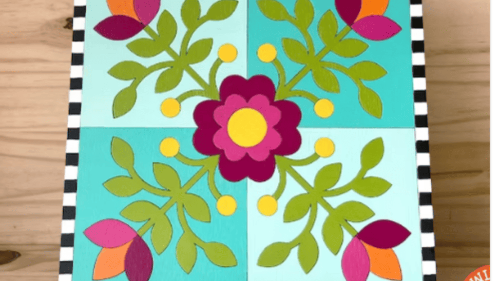 colorful barn quilt with pink flower in middle, green leaves and 4 squares