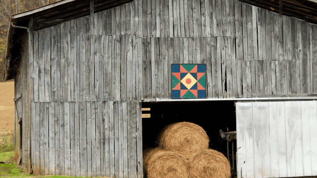 a photo of a gray barn with bright colored barn quilt