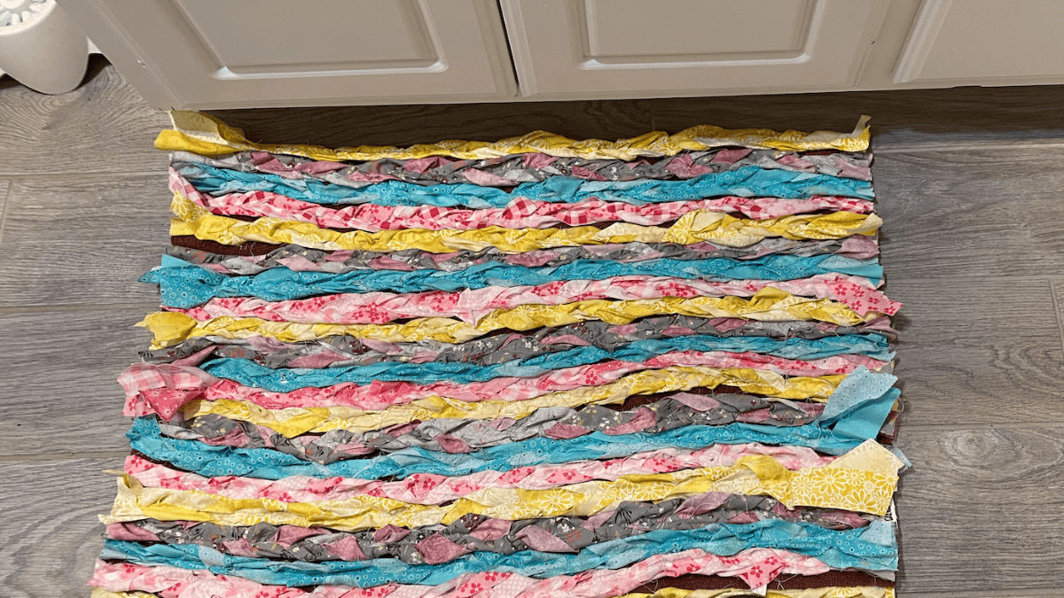 braided rag rug with yellow, pink, blue and mauve strips of fabric