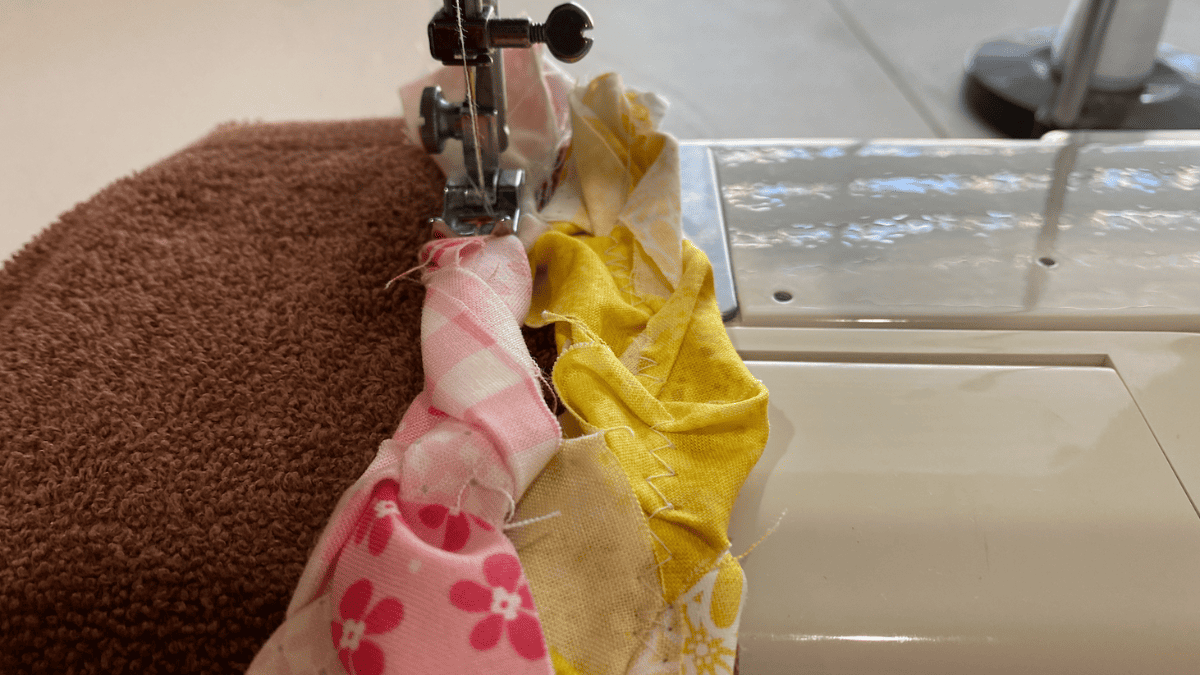 Close-up of fabric strips being braided together, showing the raw edges and varied textures of the materials.