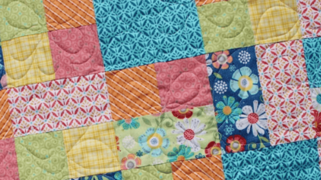 colorful quilt with blues, pinks, yellows and greens in squares and rectangles